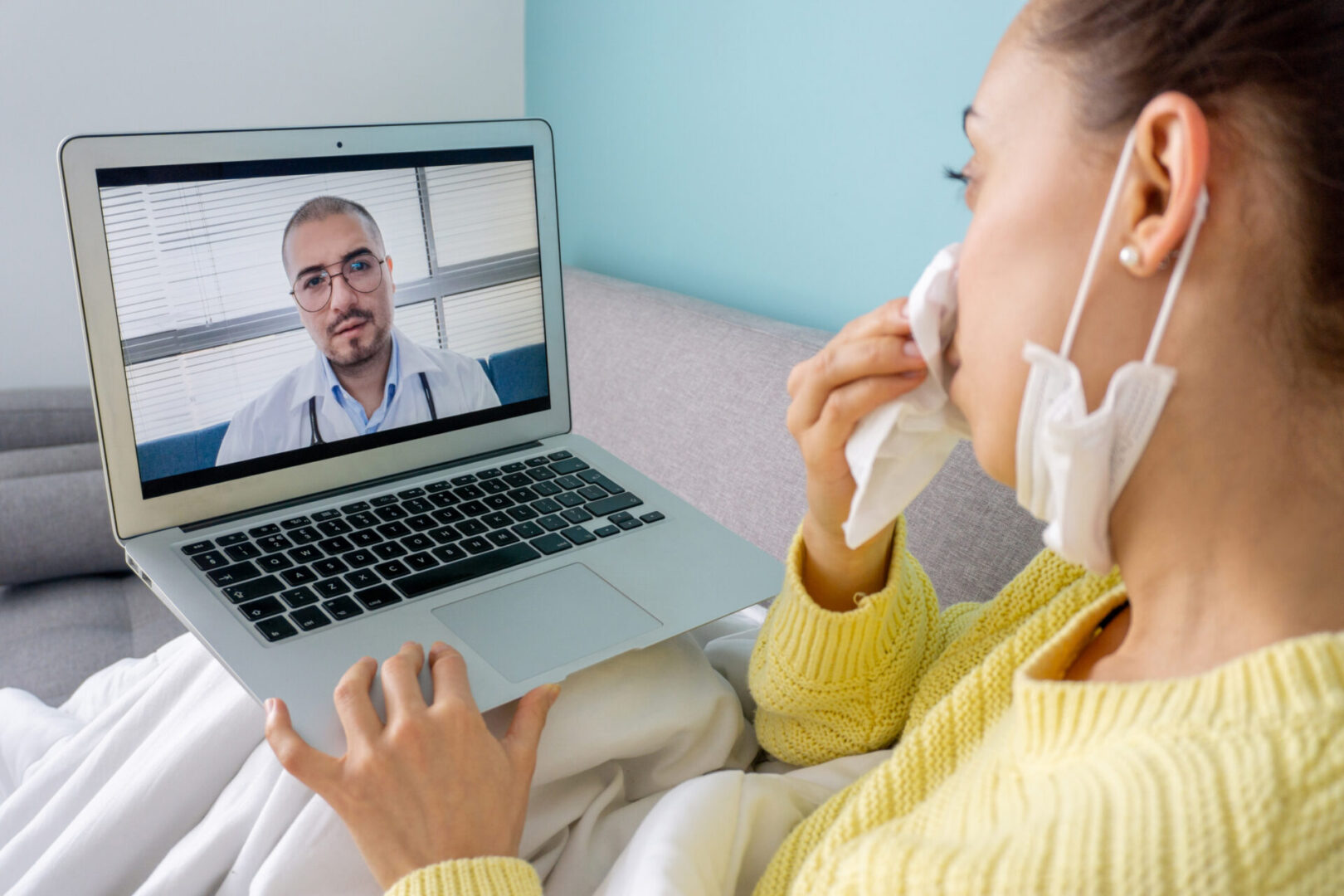 Sick woman at home talking to her doctor through a video conference on her laptop computer â telemedicine concepts